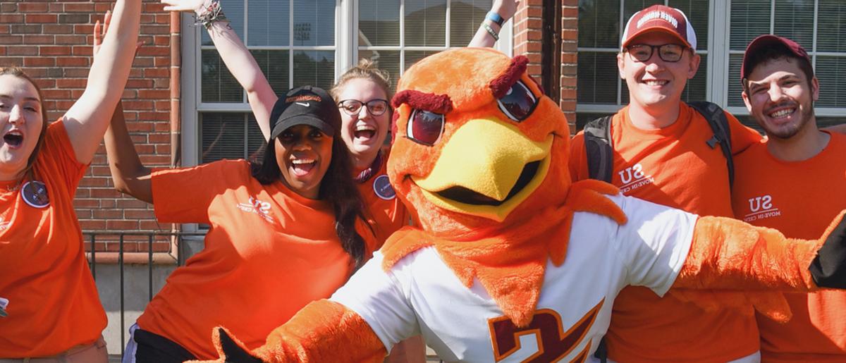 Benny Hawk mascot 和 students clad in orange cheer 和 smile for the camera.